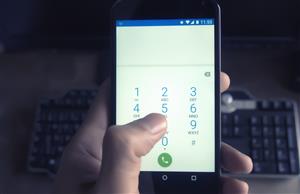 Person dialing a phone number on a mobile phone - this photo is to remind you to call in absences 